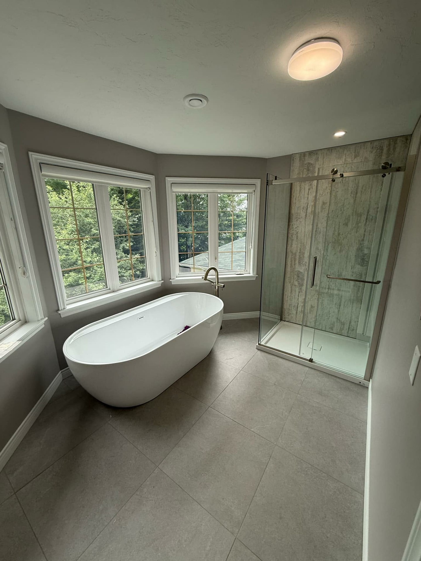 Bathroom with freestanding tub and glass shower with textured back wall installed by ERSA Plumbing