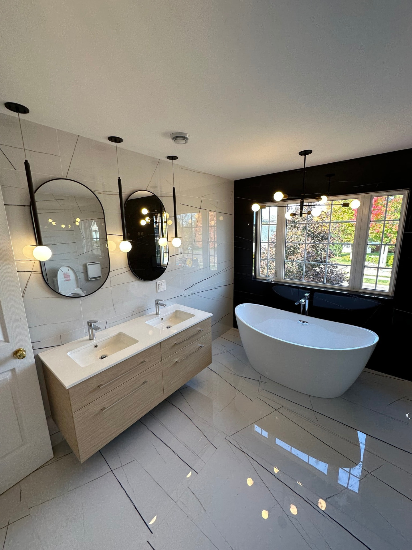 Modern bathroom with a freestanding tub in front of windows installed by ERSA Plumbing