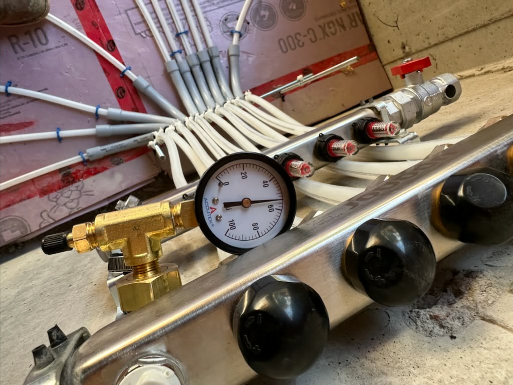 Close-up of radiant heating manifold pressure controls and connected piping