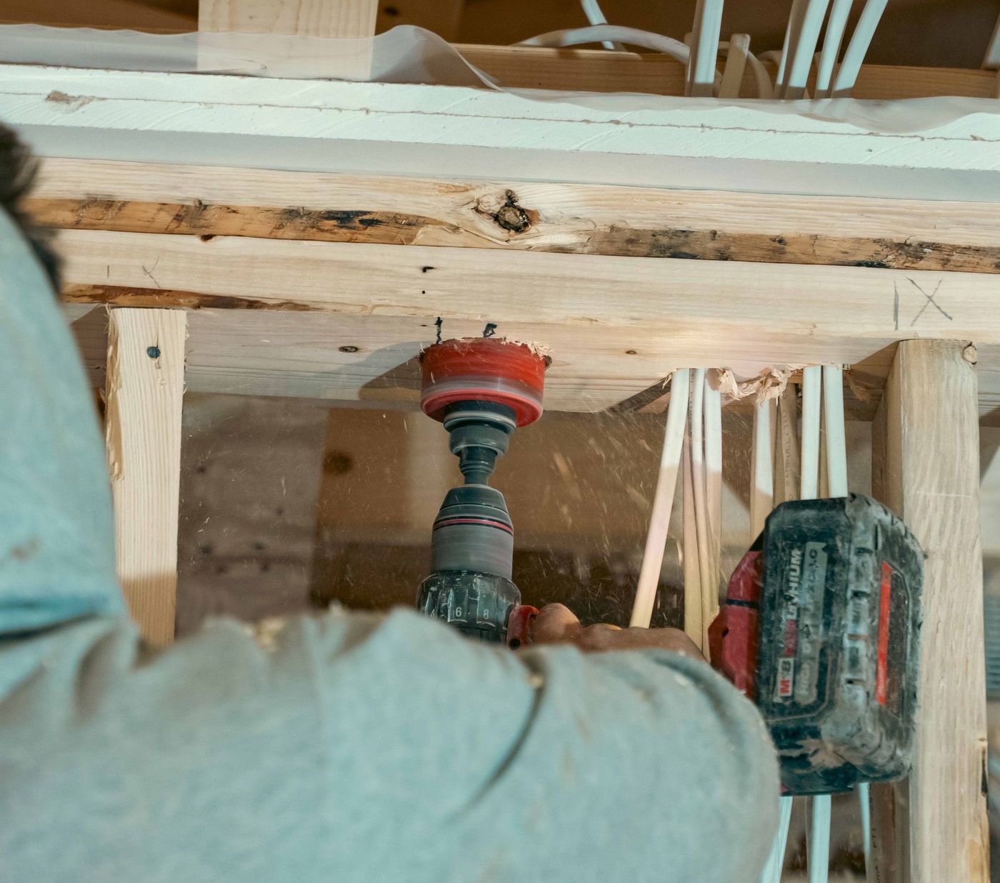 Plumber completing a plumbing rough-in inside a framed building