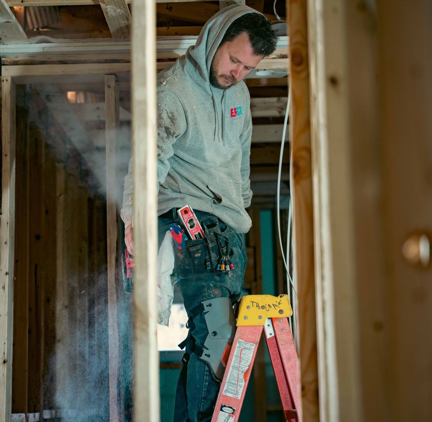 Plumber completing a plumbing rough-in inside a framed building