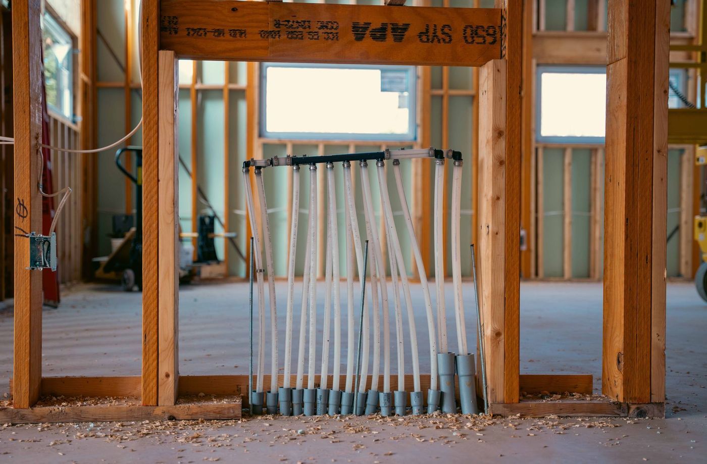 Plumber completing a plumbing rough-in inside a framed building