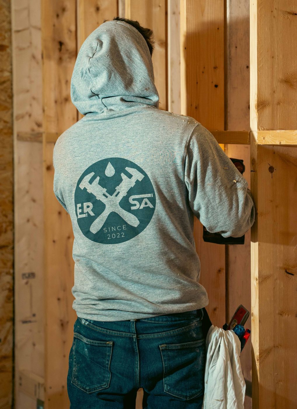 Plumber completing a plumbing rough-in inside a framed building