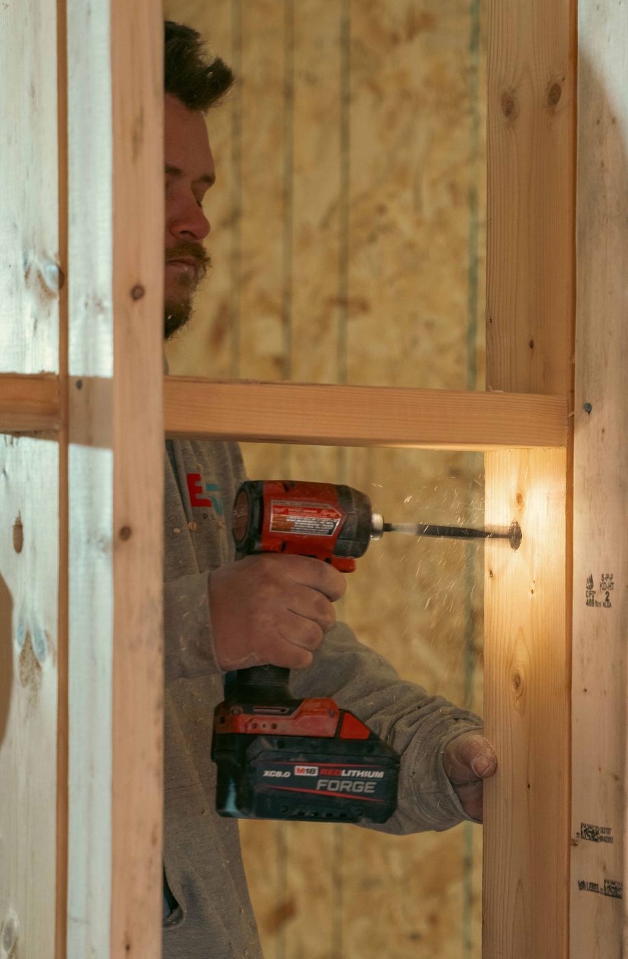 Plumber completing a plumbing rough-in inside a framed building