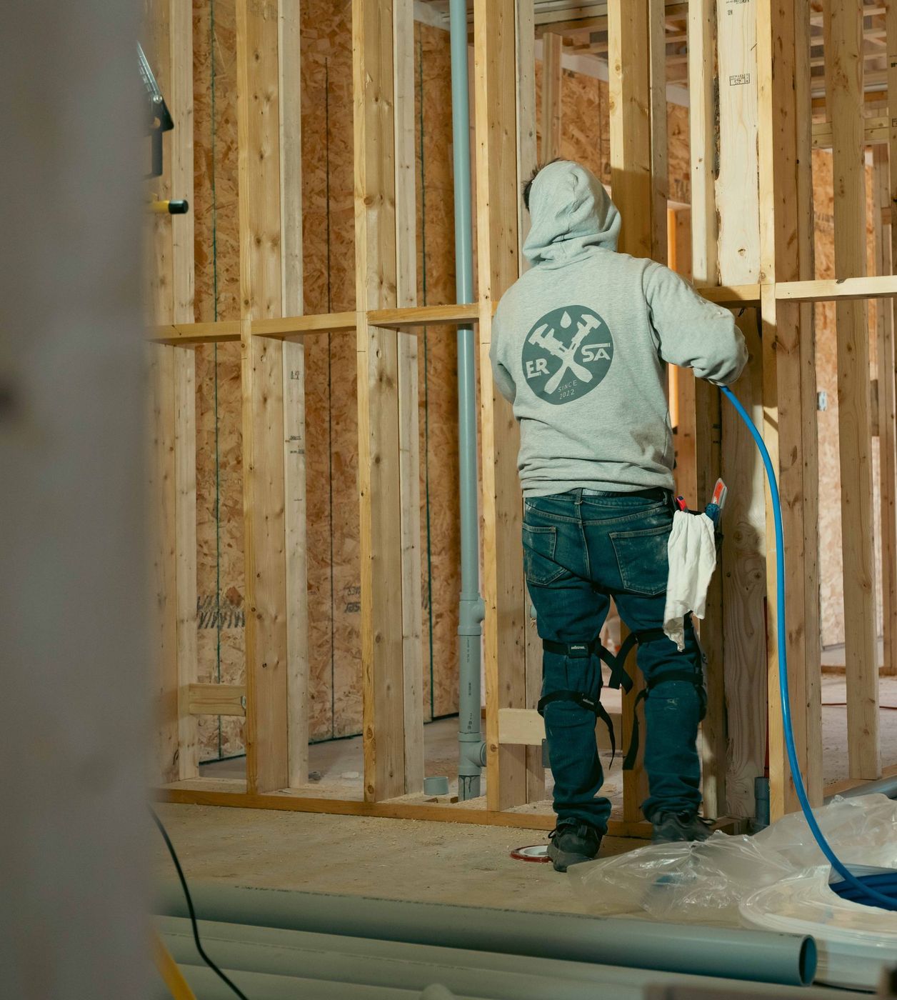 Plumber completing a plumbing rough-in inside a framed building