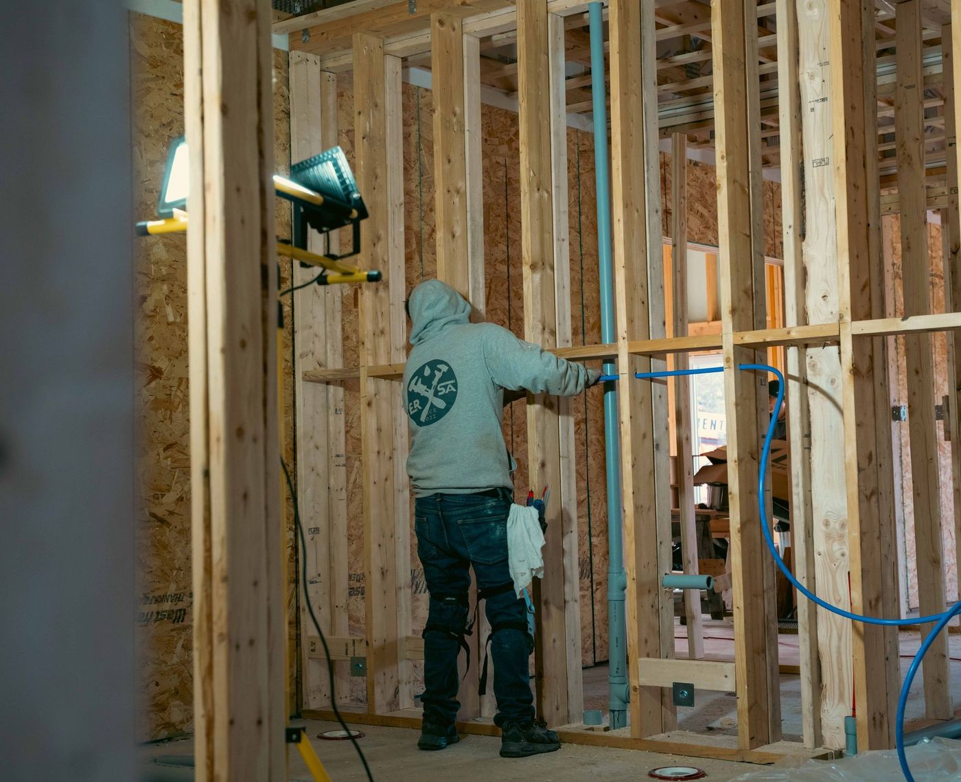 Plumber completing a plumbing rough-in inside a framed building
