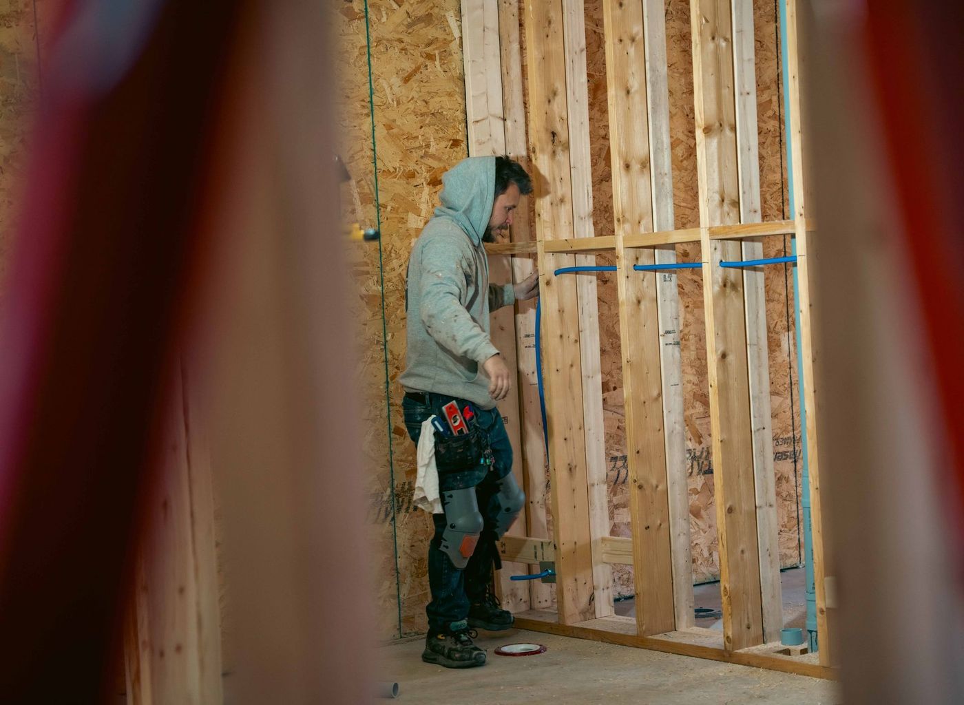 Plumber completing a plumbing rough-in inside a framed building