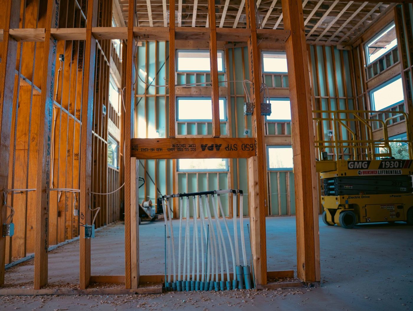 Plumber completing a plumbing rough-in inside a framed building